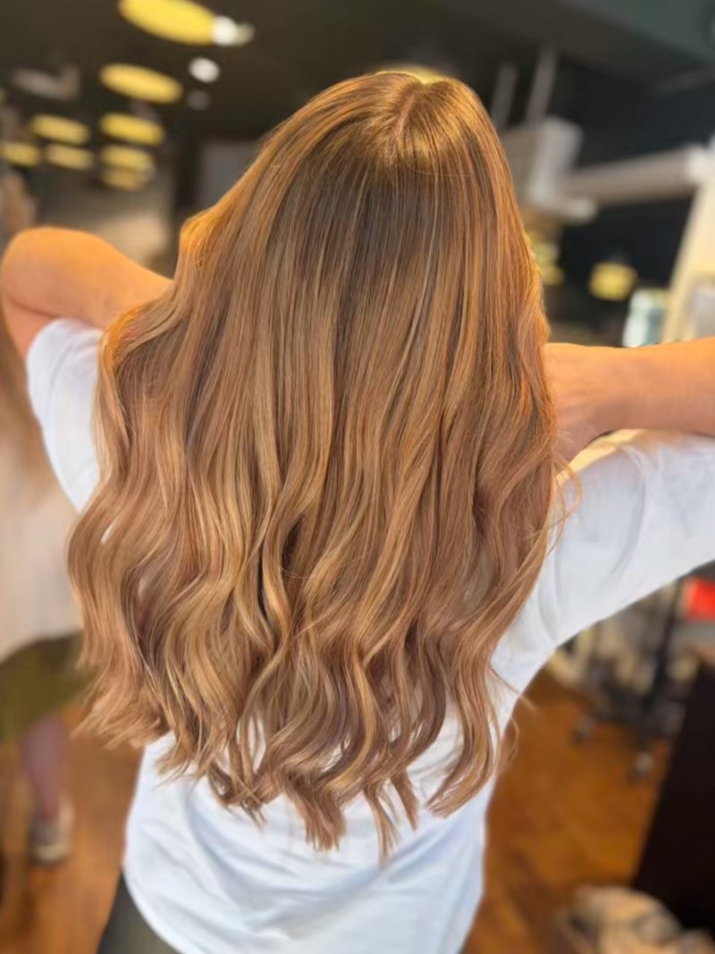 Varmt gyldent balayage med kobberskær og bløde bølger, set bagfra